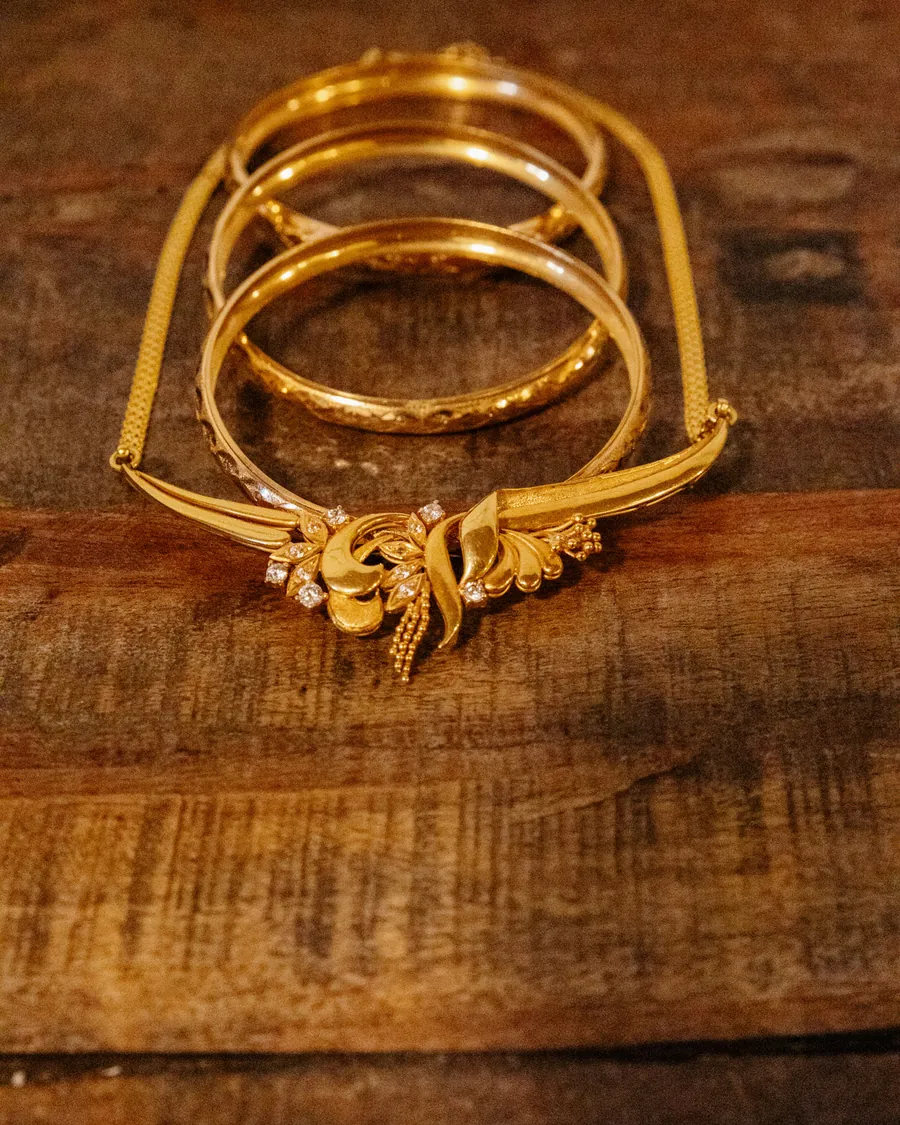 Gold bangles and a gold necklace laid out on an old wooden table