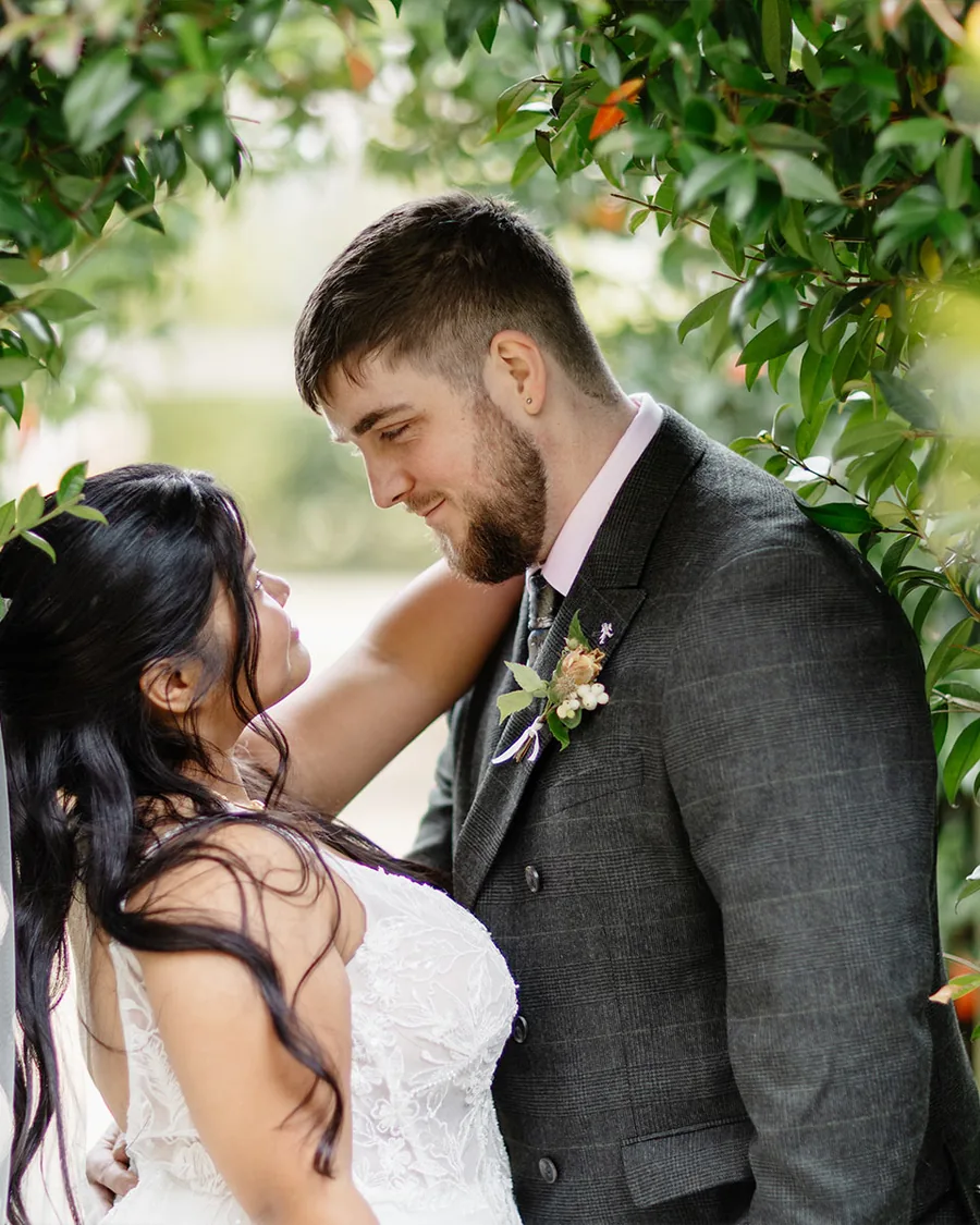 Bride and groom under an arch of green leaves