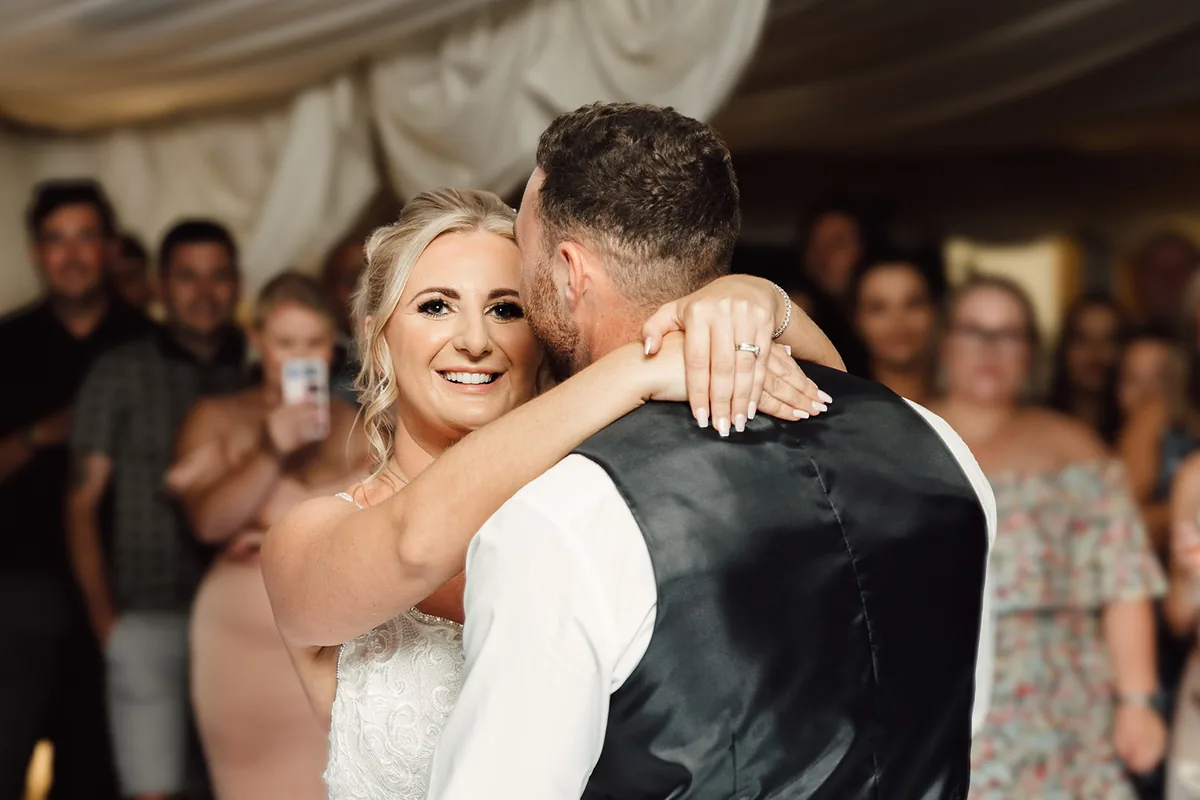 Bride and groom dancing as their guests gather round