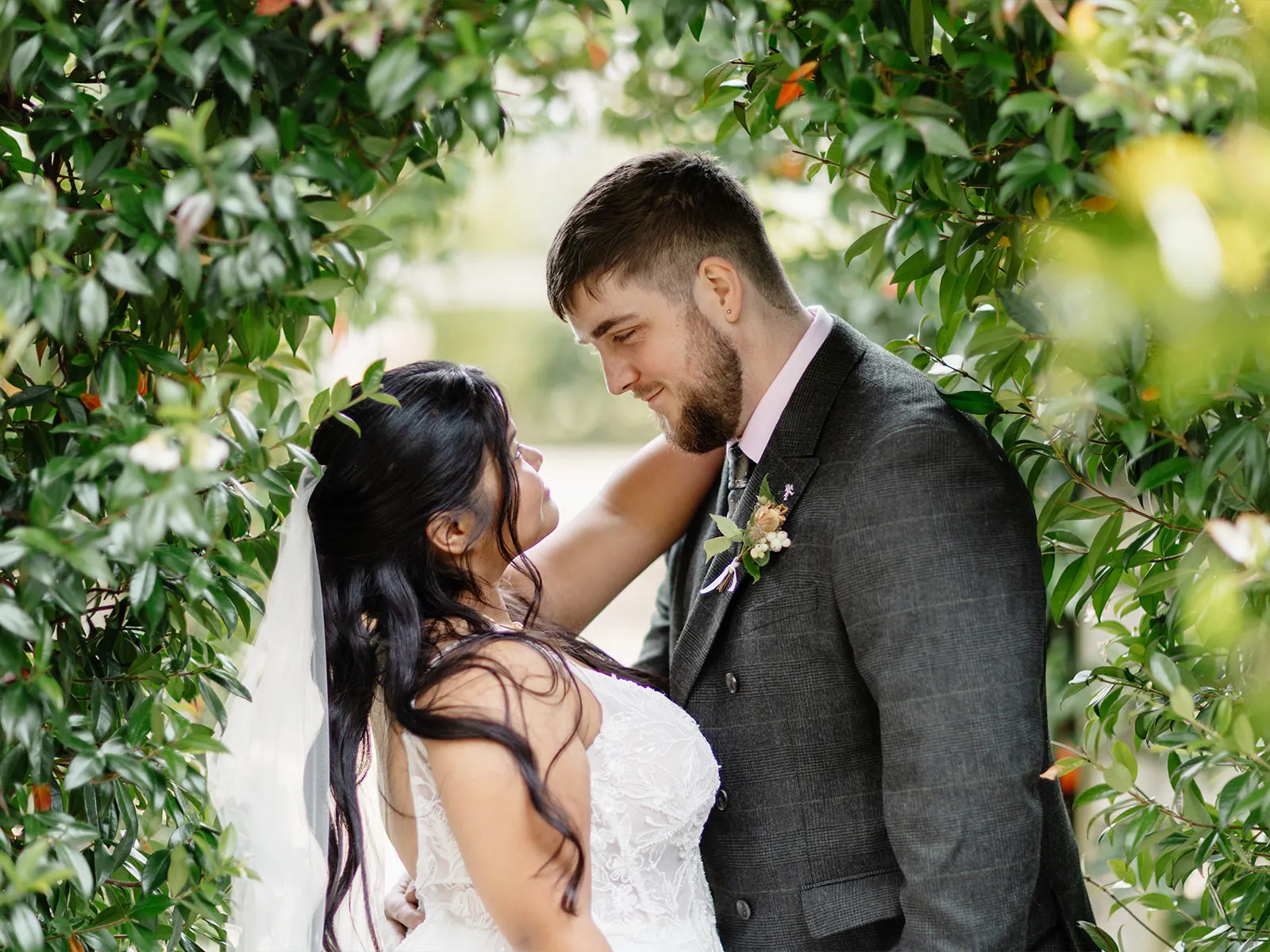 A couple laughing together under a leafy archway