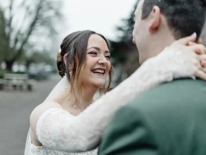 A bride smiling over her groom&rsquo;s shoulder