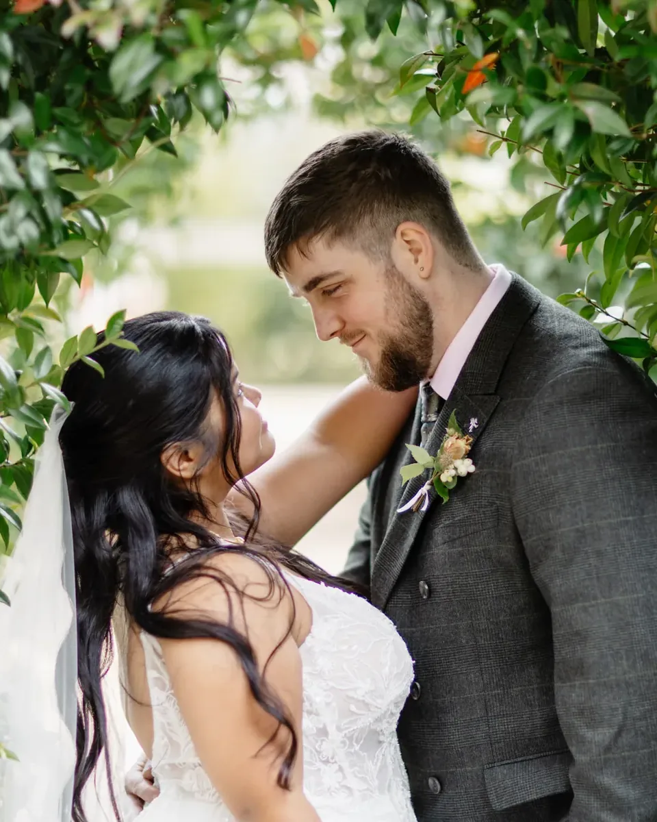 Gloria and Oliver framed by a leafy flowering arch at Coton House Farm, Lichfield