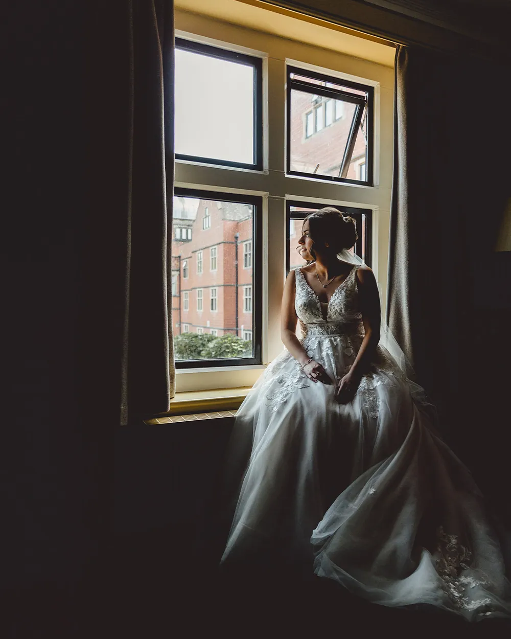 Bride sitting quietly in a window seat before the ceremony