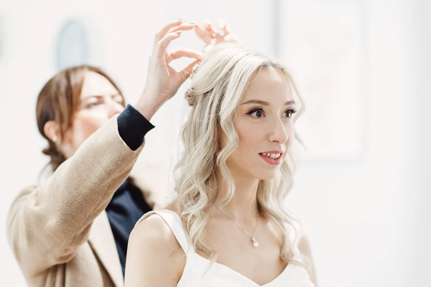 A bride having her veil placed in front of a mirror