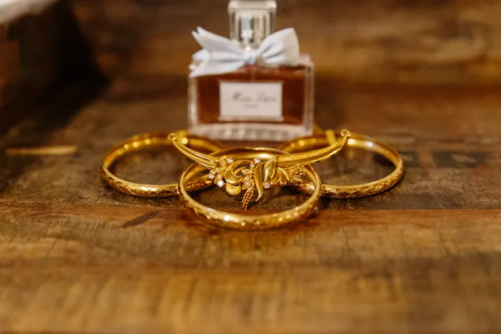 Gold bangles and a bottle of Miss Dior on an old wooden table