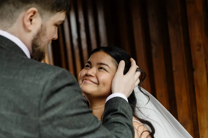 Oliver brushing Gloria&rsquo;s hair back in a wooden doorway