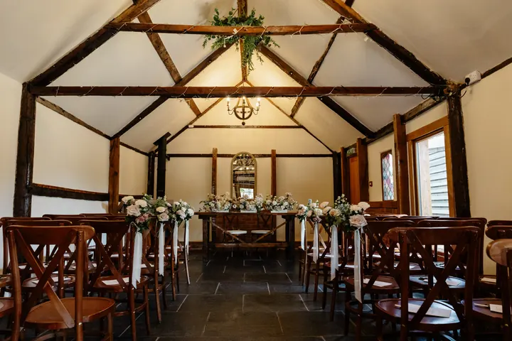 The Old Dairy Barn set for the ceremony with cross-back chairs and flowers