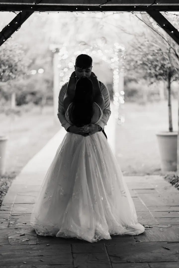 A black and white embrace beneath a garden arch