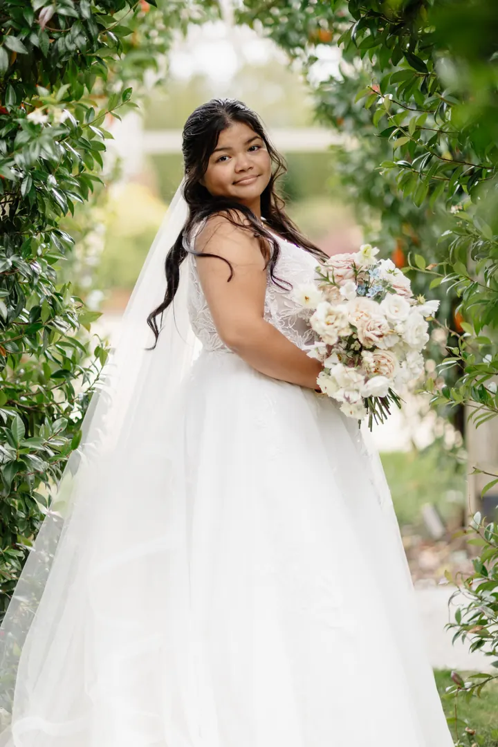 Gloria with her bouquet beneath a leafy arch
