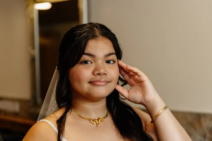 Gloria smiling in her veil and gold necklace