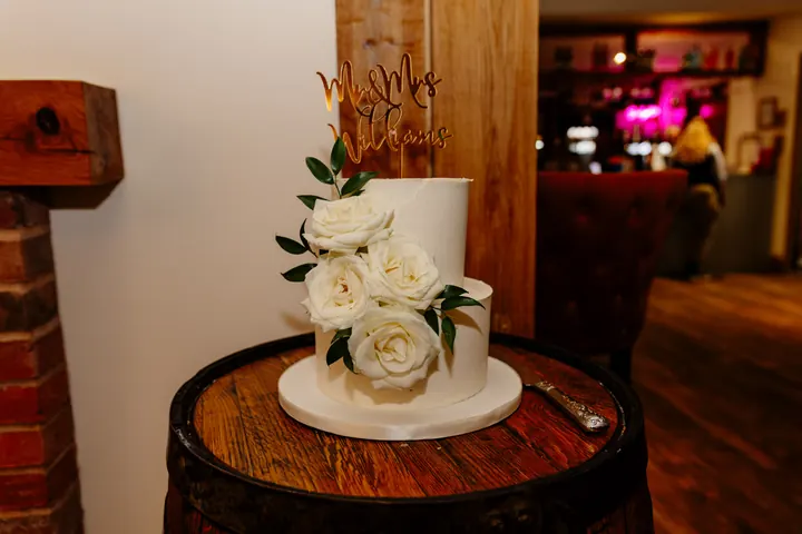 A white wedding cake with fresh roses on an old barrel