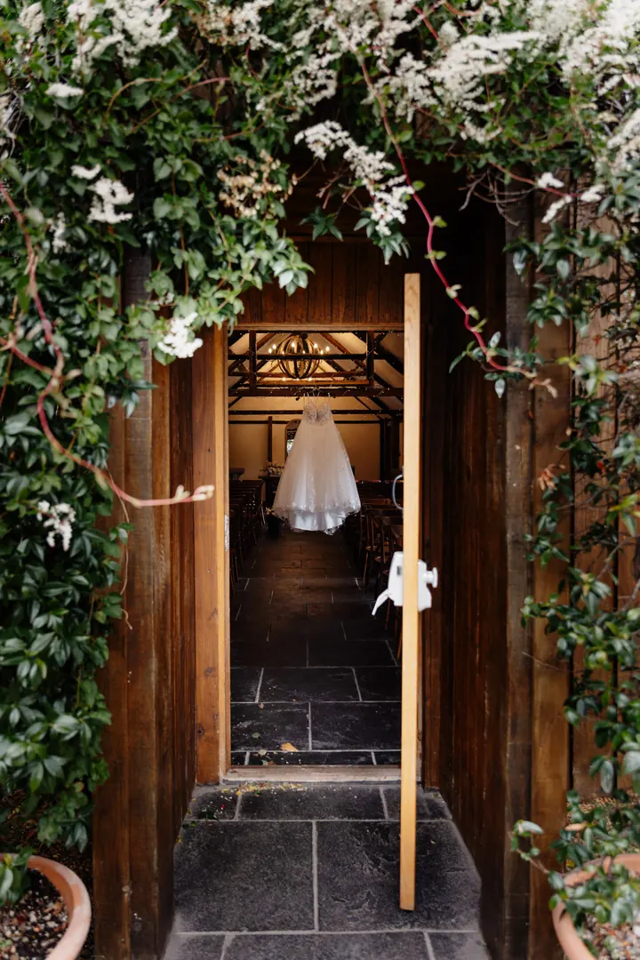The dress hanging inside the leafy doorway of the barn