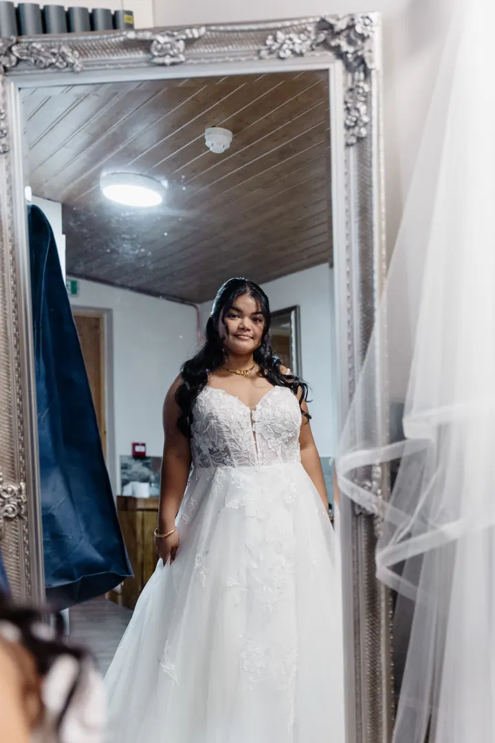 Gloria in her wedding dress, reflected in a tall mirror