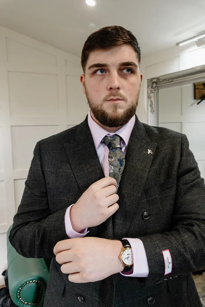 Oliver adjusting his tie in the groom&rsquo;s room