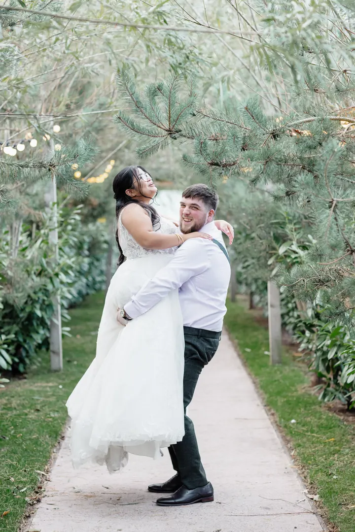 Oliver lifting Gloria in the pine walk at dusk