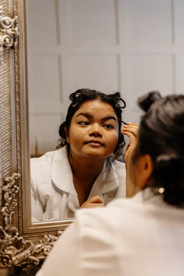 Gloria reflected in a gilded mirror during her make-up