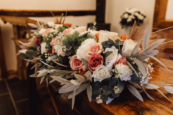 A bouquet of blush and white roses with dried grasses