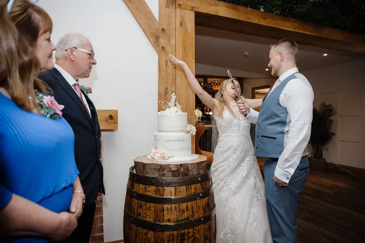 Natasha and Ryan cutting the cake on an oak barrel