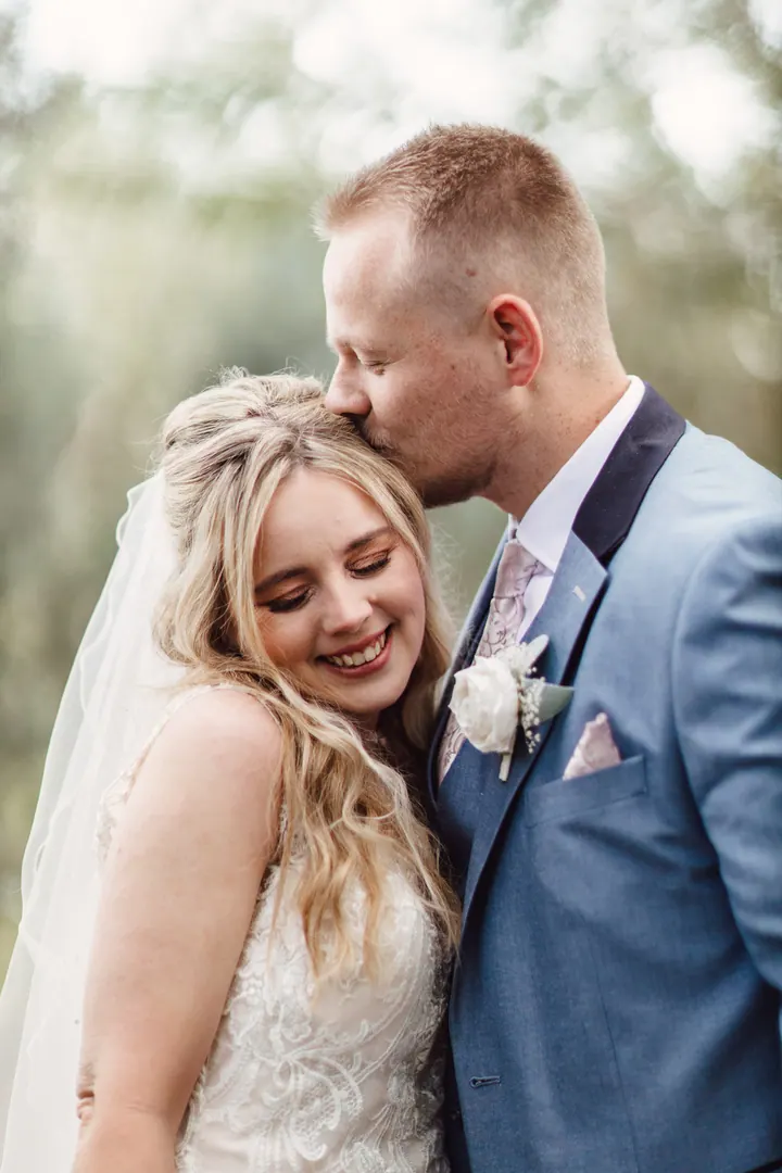 Ryan kissing Natasha&rsquo;s forehead in the willow walk at Coton House Farm