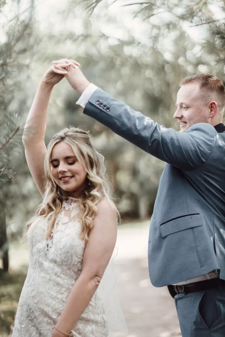 A groom twirling his bride along a willow walk at Coton House Farm