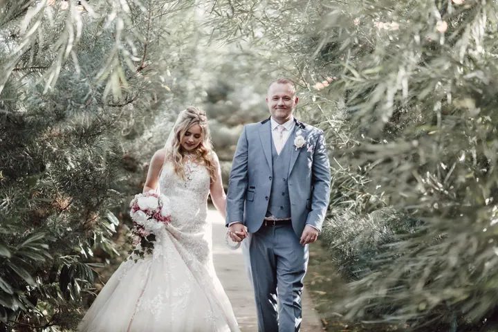 Natasha and Ryan walking hand in hand between the willows