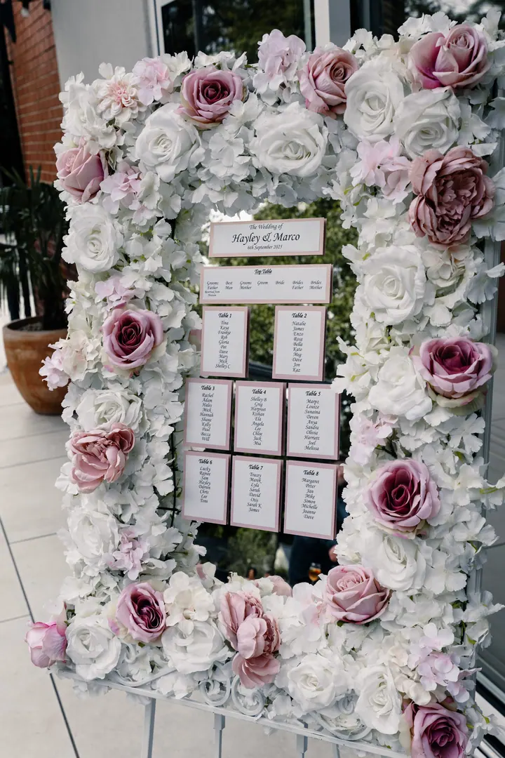 A floral table plan framed in pink and white roses