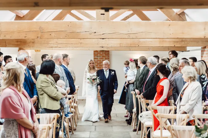 Cicely walking down the aisle with her dad as guests turn to look