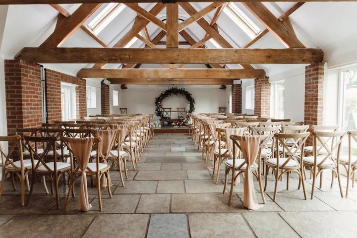 The empty ceremony barn at Hanbury Wedding Barn, with exposed oak trusses, skylights and cross-back chairs
