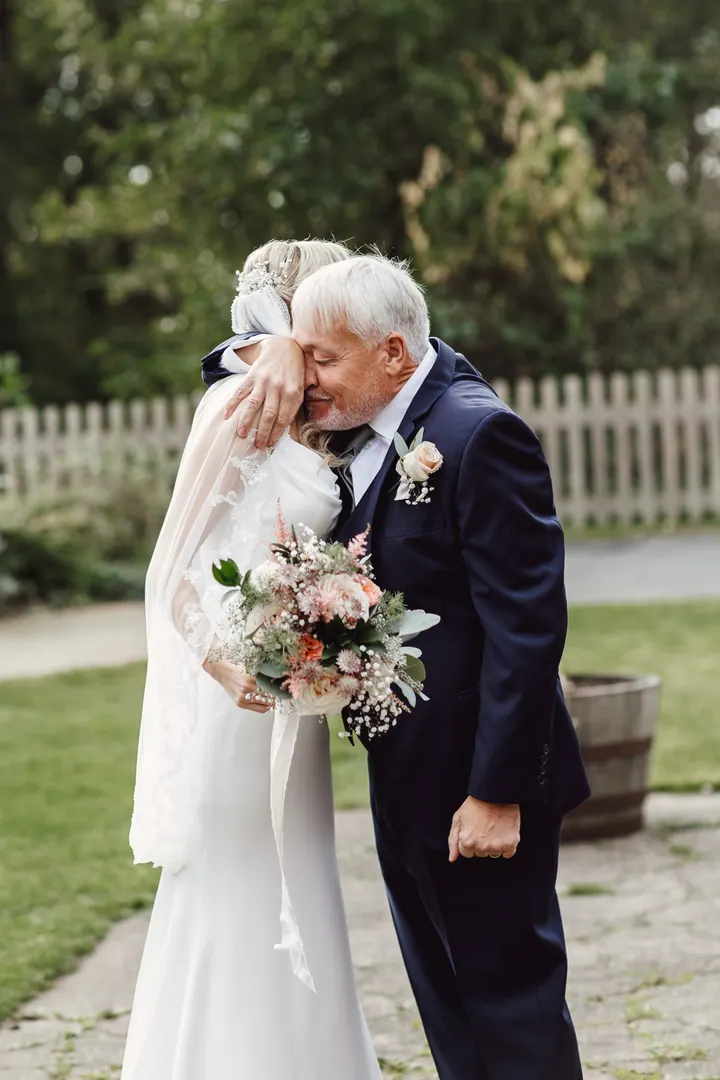 Cicely hugging her dad in the gardens before the ceremony