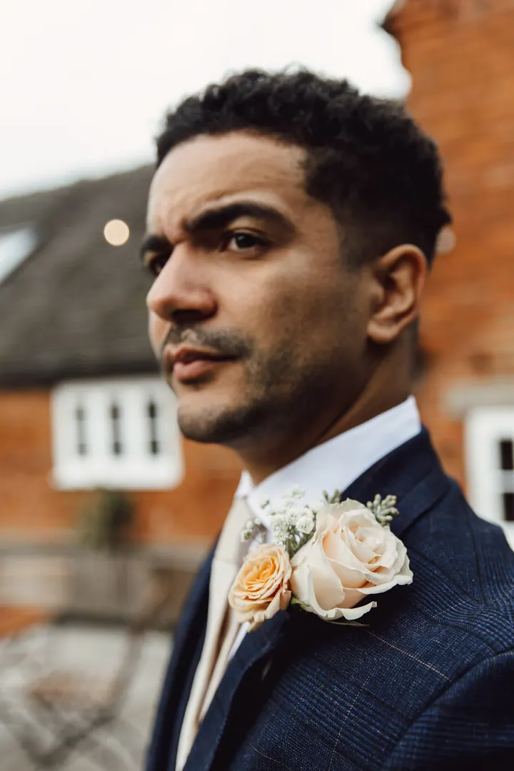 Portrait of Nathan in his navy check suit in the courtyard