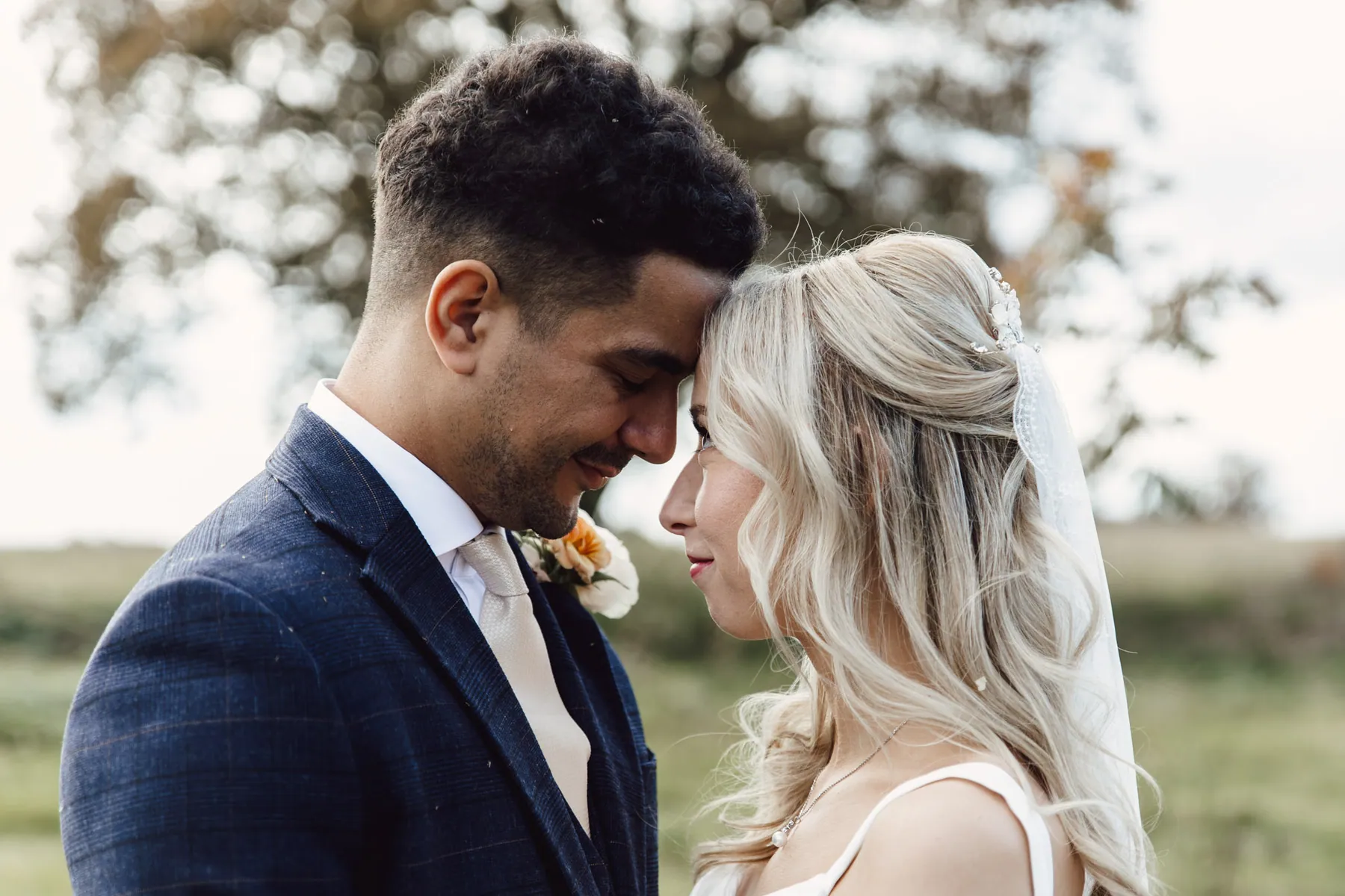 Cicely and Nathan forehead to forehead in a field, shown after editing