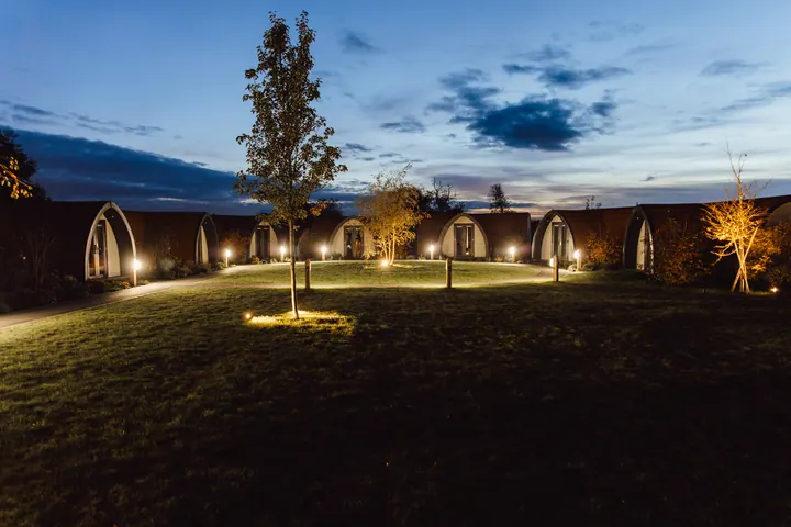 The lodges and lawn at Hanbury Wedding Barn glowing at dusk