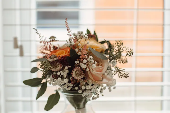 A jar of peach roses, astilbe and gypsophila arranged by the bride&rsquo;s mum