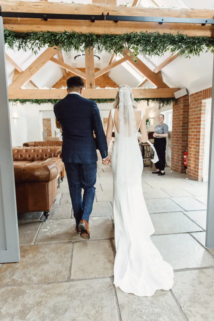 Cicely and Nathan walking out together, her veil trailing behind