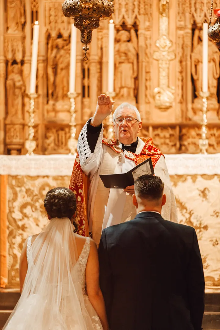 The priest giving a blessing at the gold altar