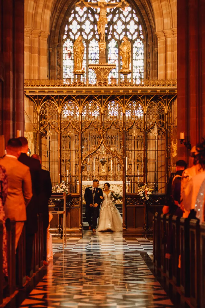 The couple at the altar beneath a glowing gold screen and stained glass window