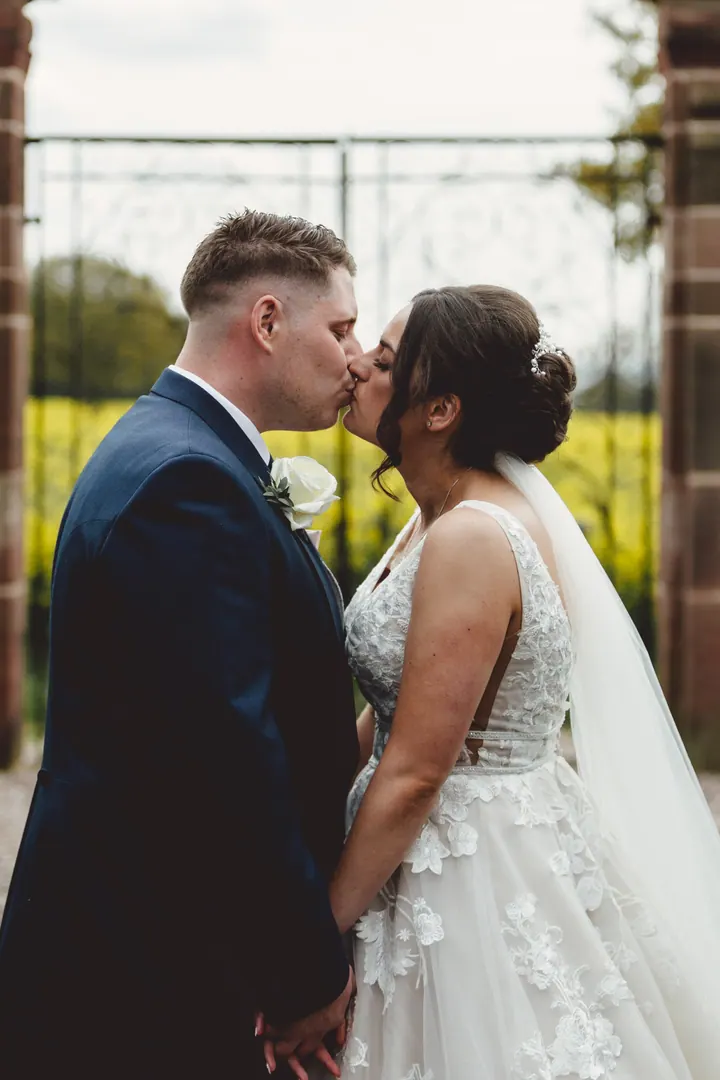 A kiss by an iron gate looking out over a rapeseed field