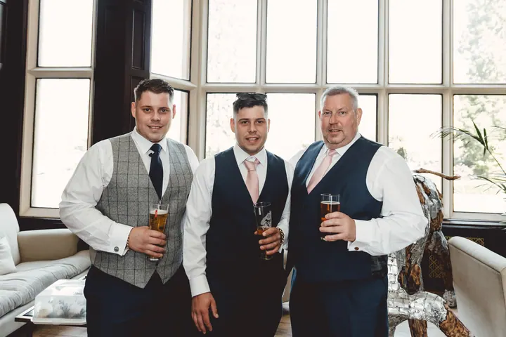 Harry and two of his groomsmen with drinks in hand