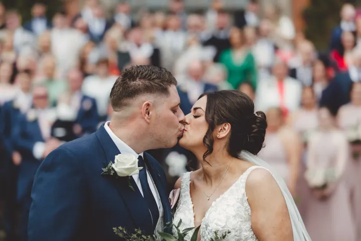 Harry and Hannah kissing in front of their cheering guests