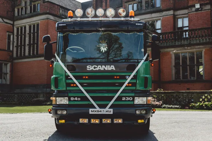 A green Scania lorry dressed with white wedding ribbons outside Hoar Cross Hall
