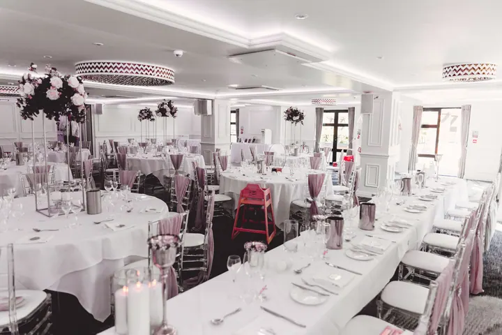 The wedding breakfast room set with round tables and pink accents