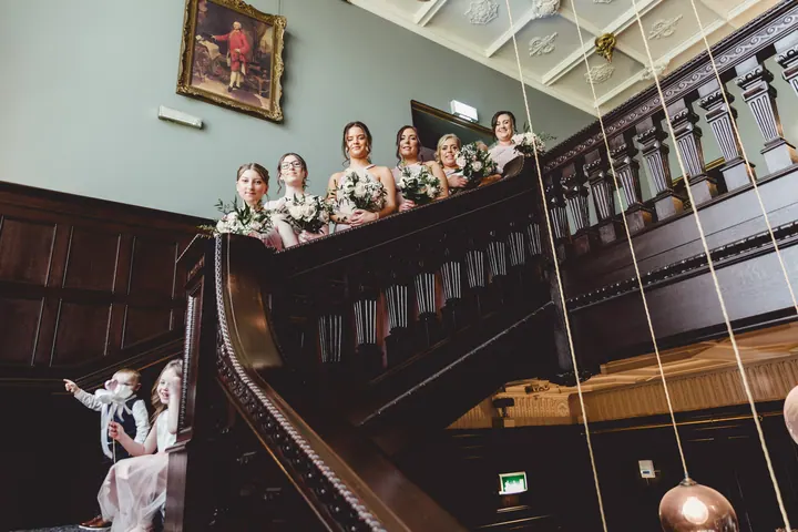 Bridesmaids waving from the balcony of the oak-panelled staircase