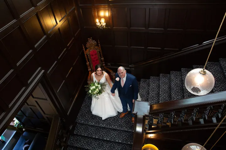 Hannah and her dad walking down the grand staircase, seen from above