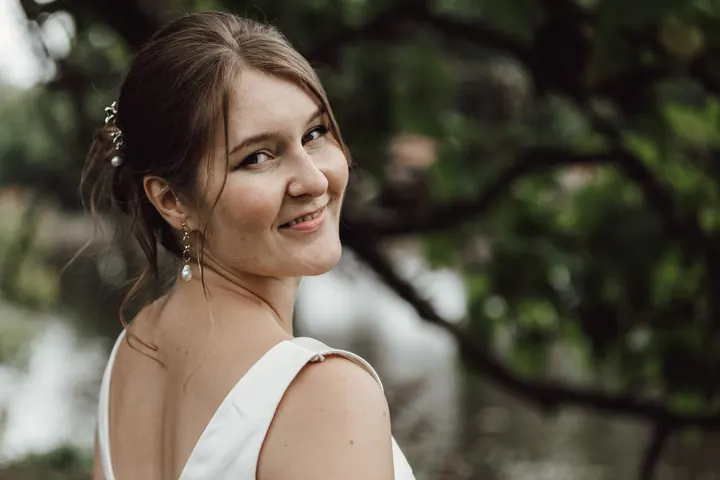 Aleks smiling over her shoulder by the pool