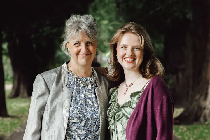 Two guests smiling together under the trees