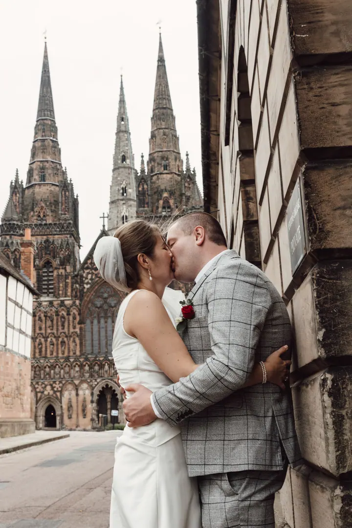 Aleks and Jamie kissing in front of the three spires of Lichfield Cathedral