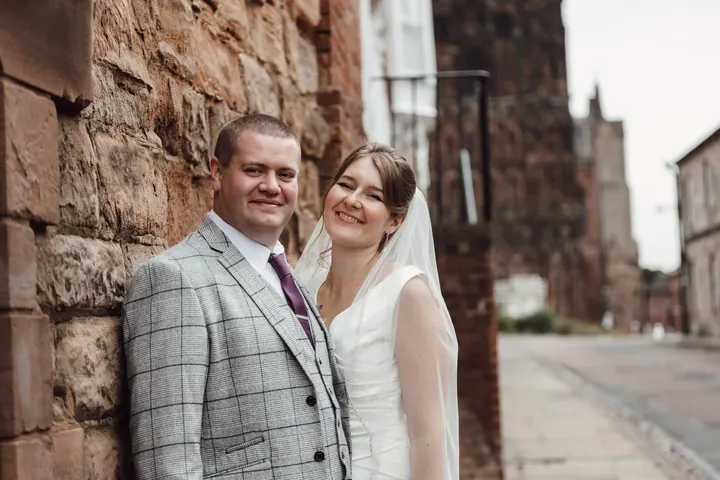 Aleks and Jamie against warm red sandstone near the cathedral