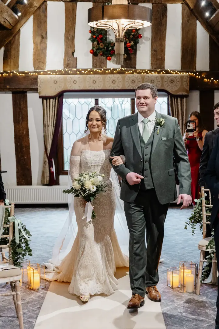 Sam walking down the aisle under the fairy-lit beams