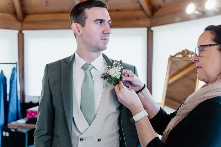 A buttonhole being pinned to Andrew&rsquo;s jacket