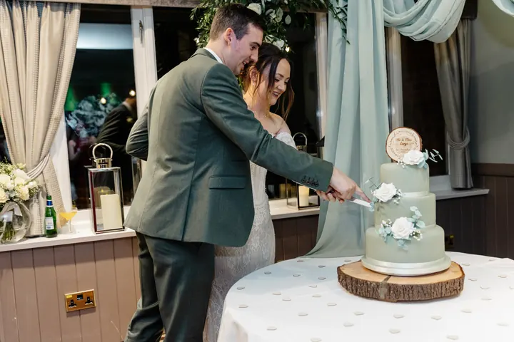 Sam and Andrew cutting the sage green cake
